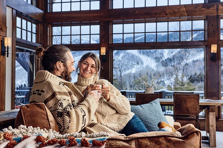 Couple enjoying hot cocoa while relaxing on the couch on a cold, snowy day.