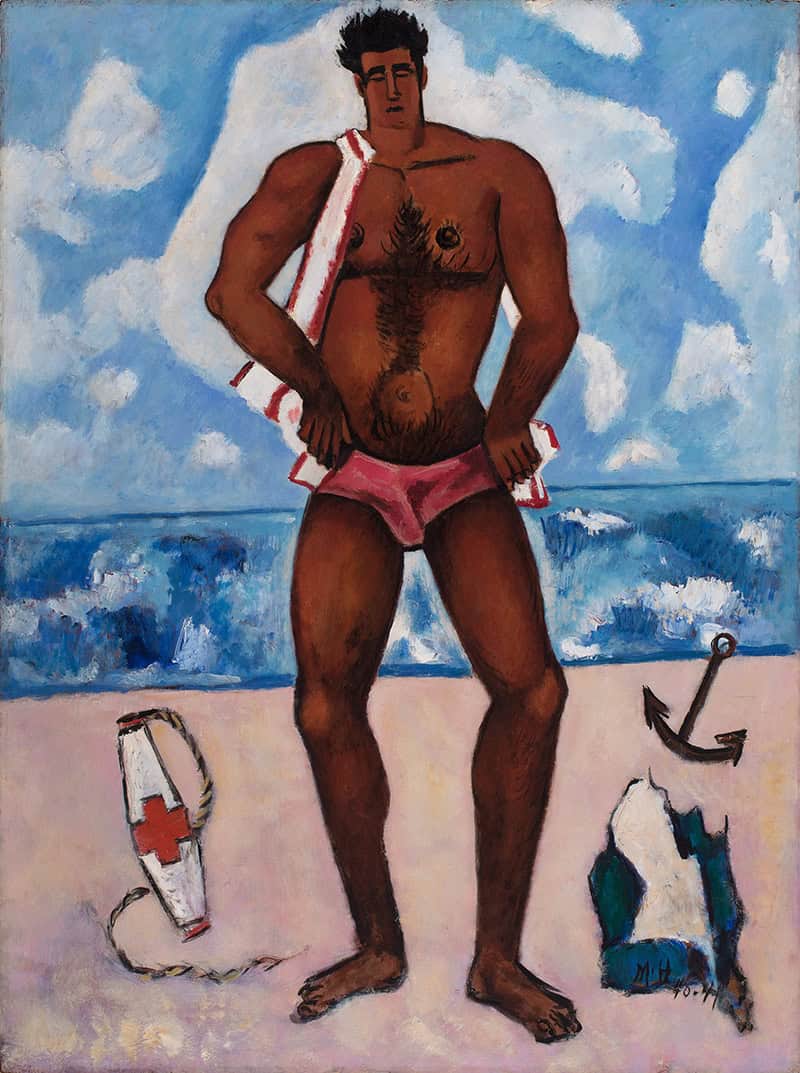 A muscular man in pink trunks stands on a beach with a towel over his shoulder. Nearby are a lifebuoy, anchor, and beach sculpture. Blue sky and sea are in the background.