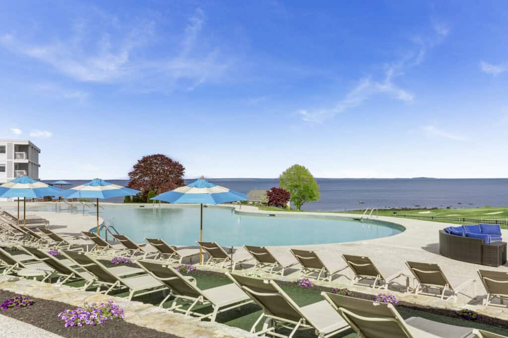 A pool with chairs and umbrellas by the water.