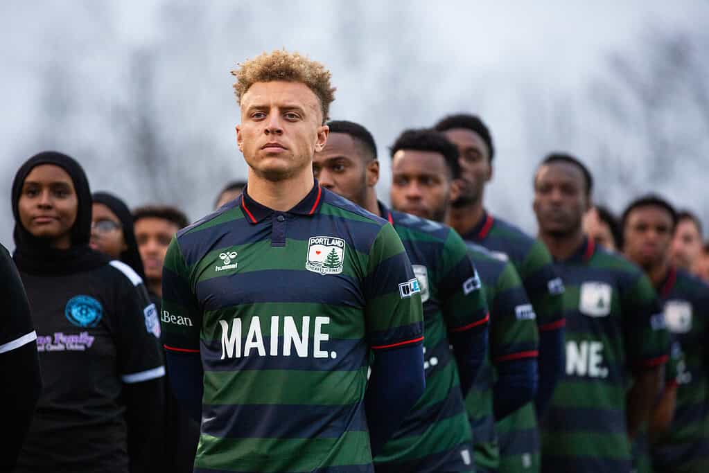 Hearts of Pine soccer players standing side by side with striped green and navy jerseys