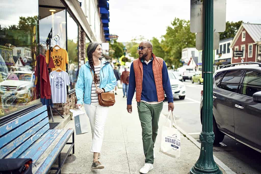Vibrant Maine street scene featuring shoppers enjoying local stores and colorful storefronts in a charming coastal town.
