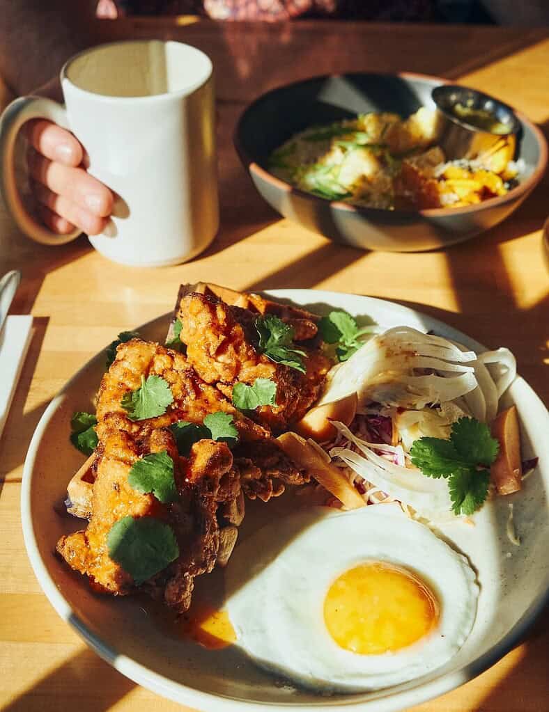 plate pf eggs and hash and a hand holding a coffee cup