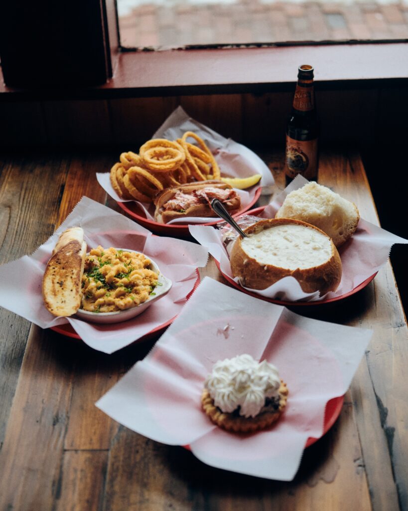 table with mac and cheese, blueberry pie, chowder in a bread bowl and a lobster roll with onion rings