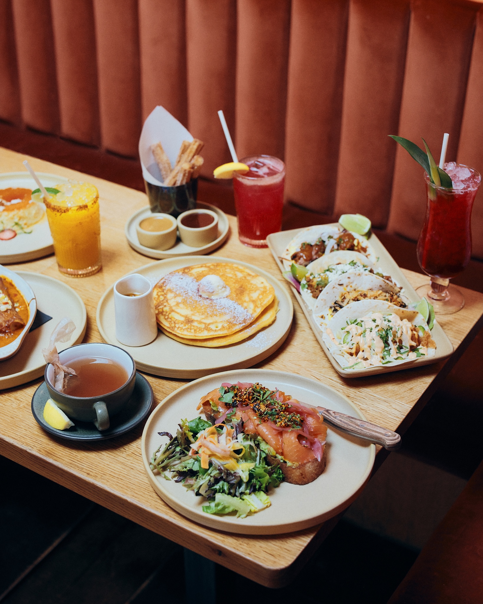 orange booth and a table covered in brunch dishes like pancakes and tacos
