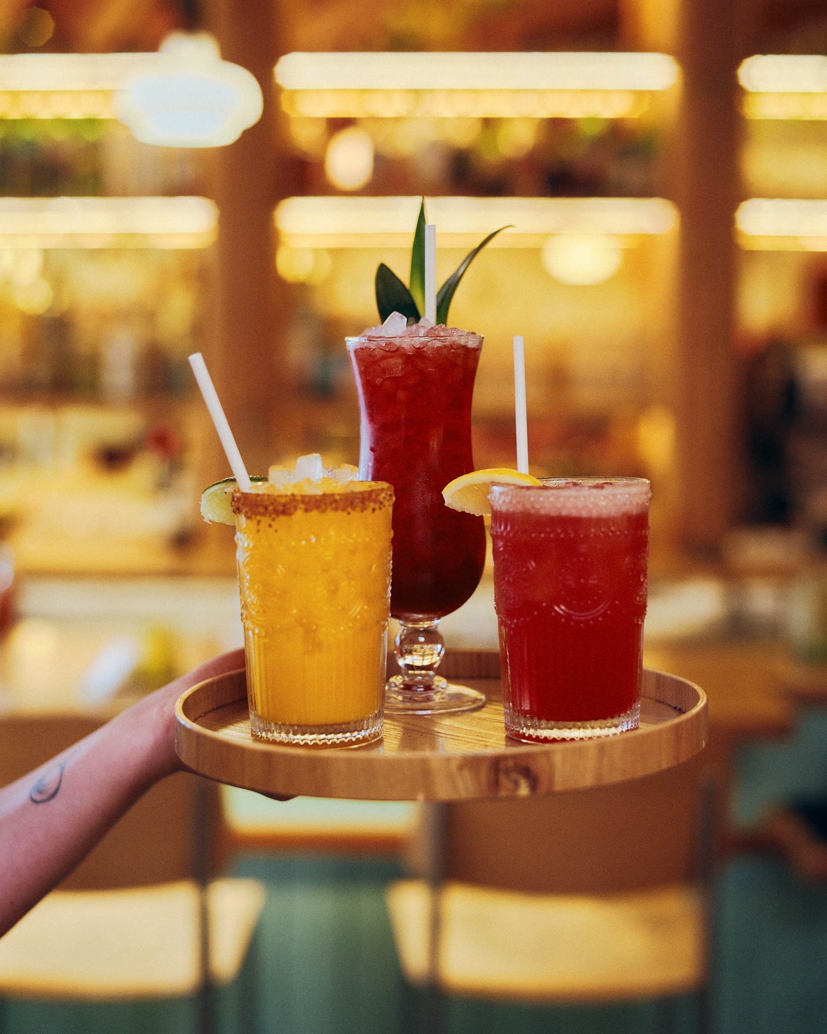 hand holding a tray of tropical drinks with colorful garnishes
