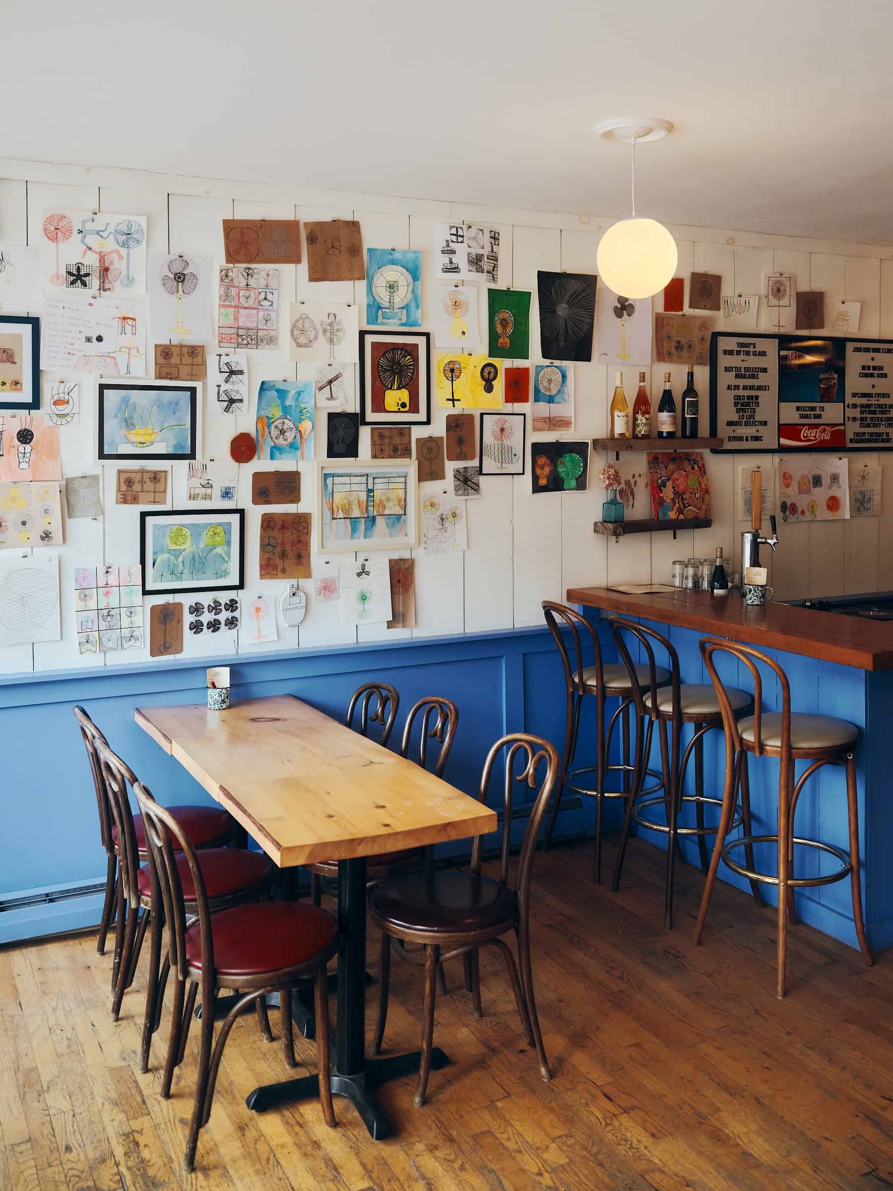 restaurant with tables and chairs, cornflower blue wainscotting and pictures on the walls